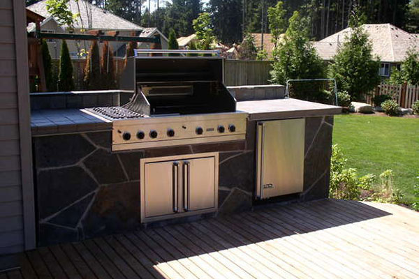 Create a unique space in your backyard with an outdoor grill and kitchen designed by Bonney Lake Landscapes in Seattle, Washington.